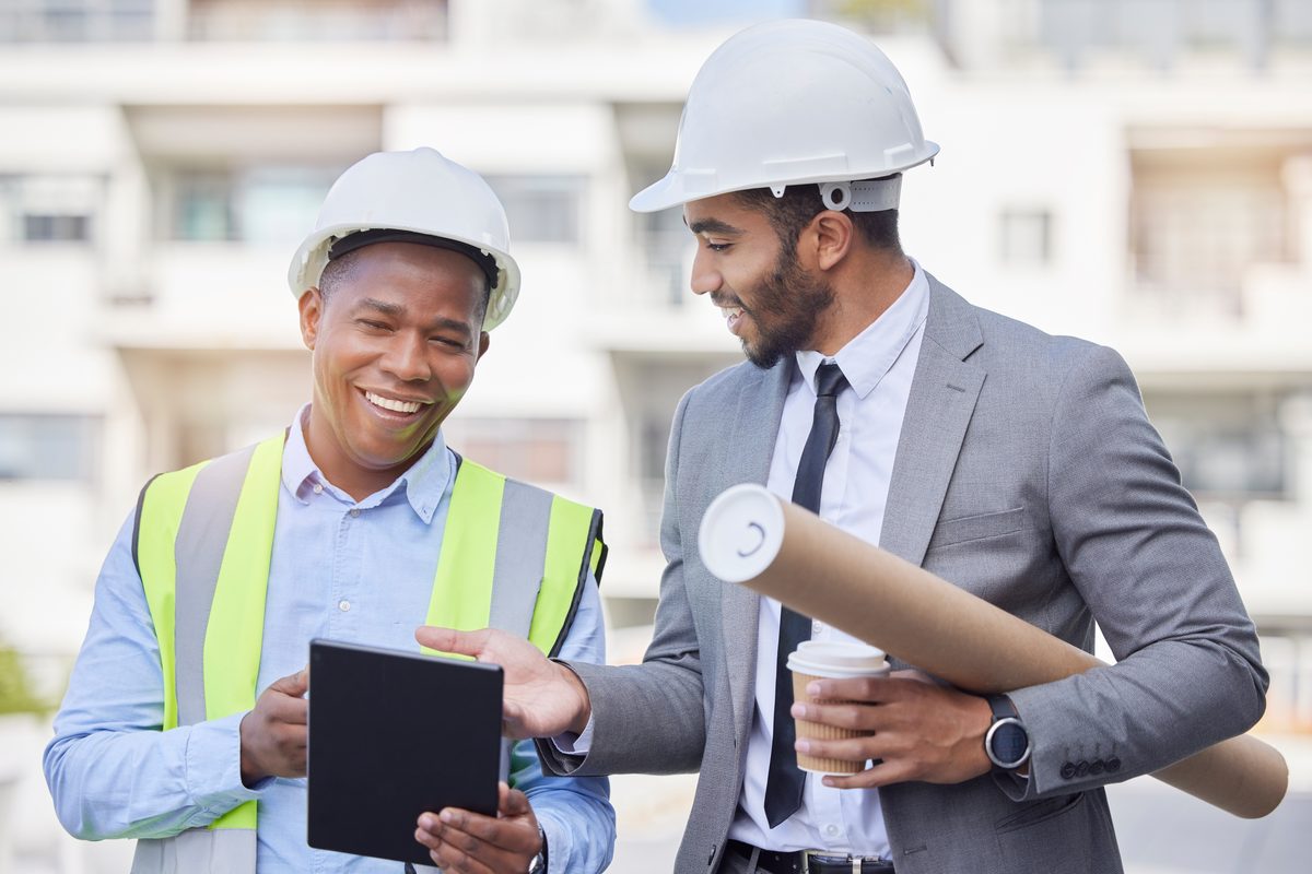 Contractor in a hard hat reviewing plans with a client on a job site
