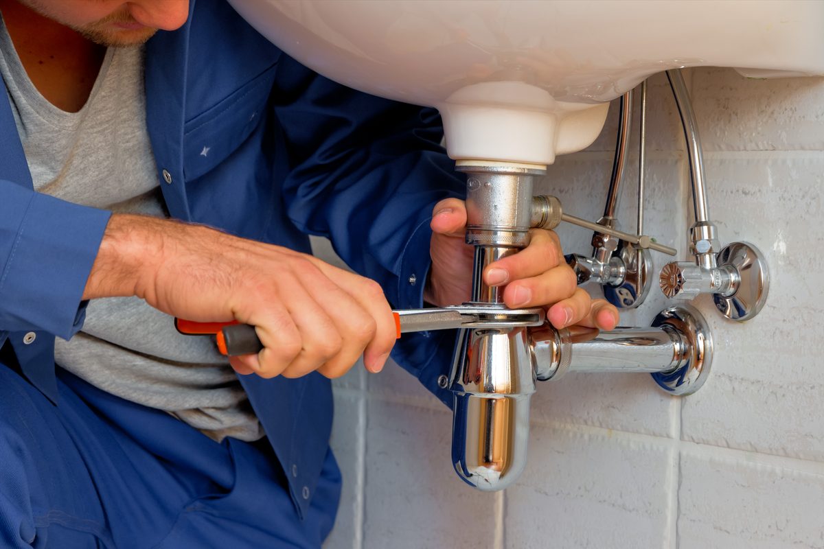 Plumber repairing pipes under a kitchen sink